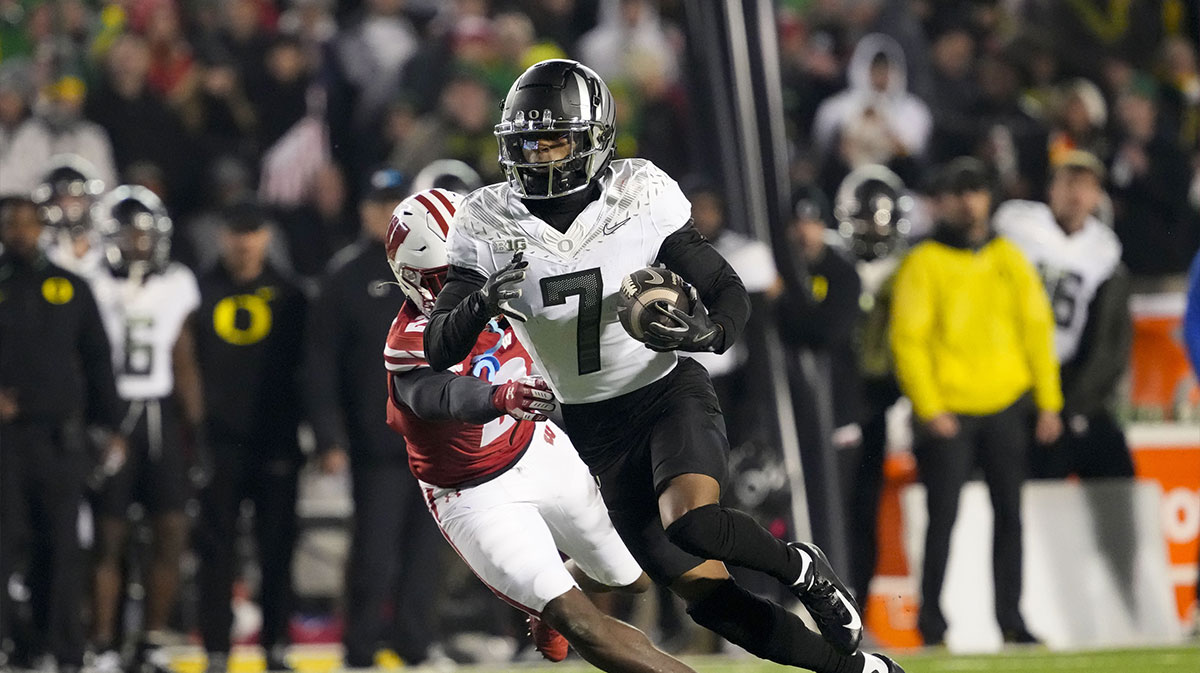Nov 16, 2024; Madison, Wisconsin, USA; Oregon Ducks wide receiver Evan Stewart (7) rushes with the football in front of Wisconsin Badgers cornerback Ricardo Hallman (2) after catching a pass during the fourth quarter at Camp Randall Stadium.