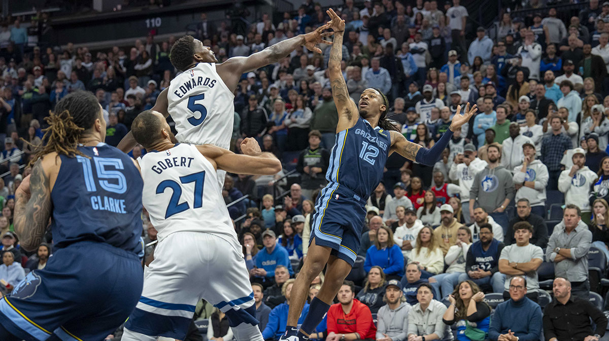 Memphis Grizzlies guard Ja Morant (12) falls back after releasing the game winning shot over Minnesota Timberwolves guard Anthony Edwards (5) in the second half at Target Center. 