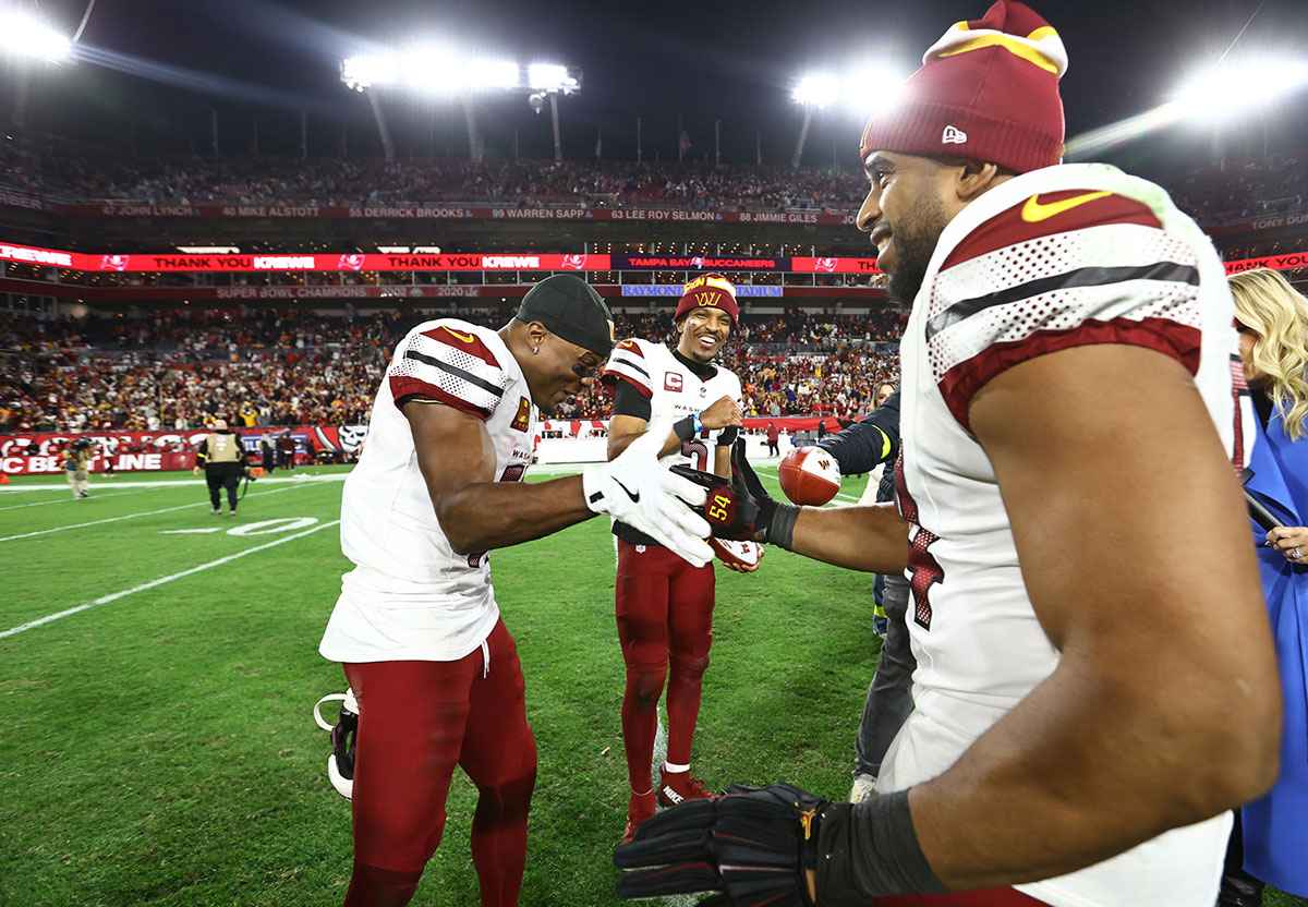 Washington Commanders quarterback Jayden Daniels (5) celebrates with wide receiver Terry McLaurin (17) and linebacker Bobby Wagner (54) after winning a NFC wild card playoff against the Tampa Bay Buccaneers at Raymond James Stadium.