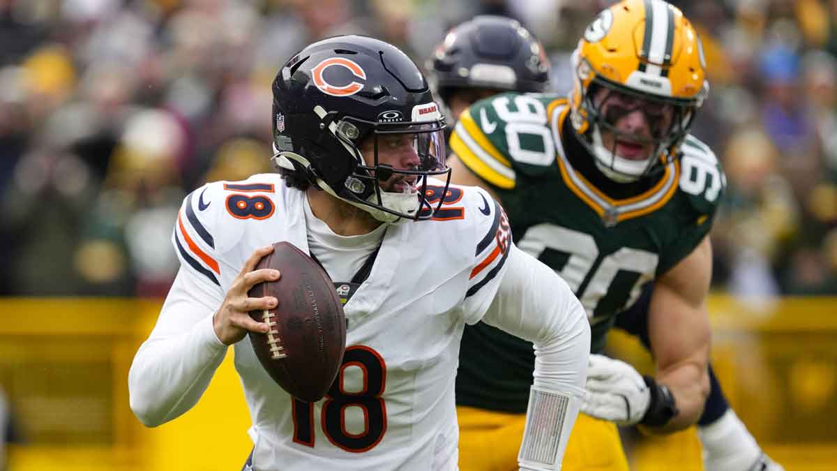 Chicago Bears quarterback Caleb Williams (18) scrambles away from pressure applied by Green Bay Packers defensive lineman Lukas Van Ness (90) during the first quarter at Lambeau Field.