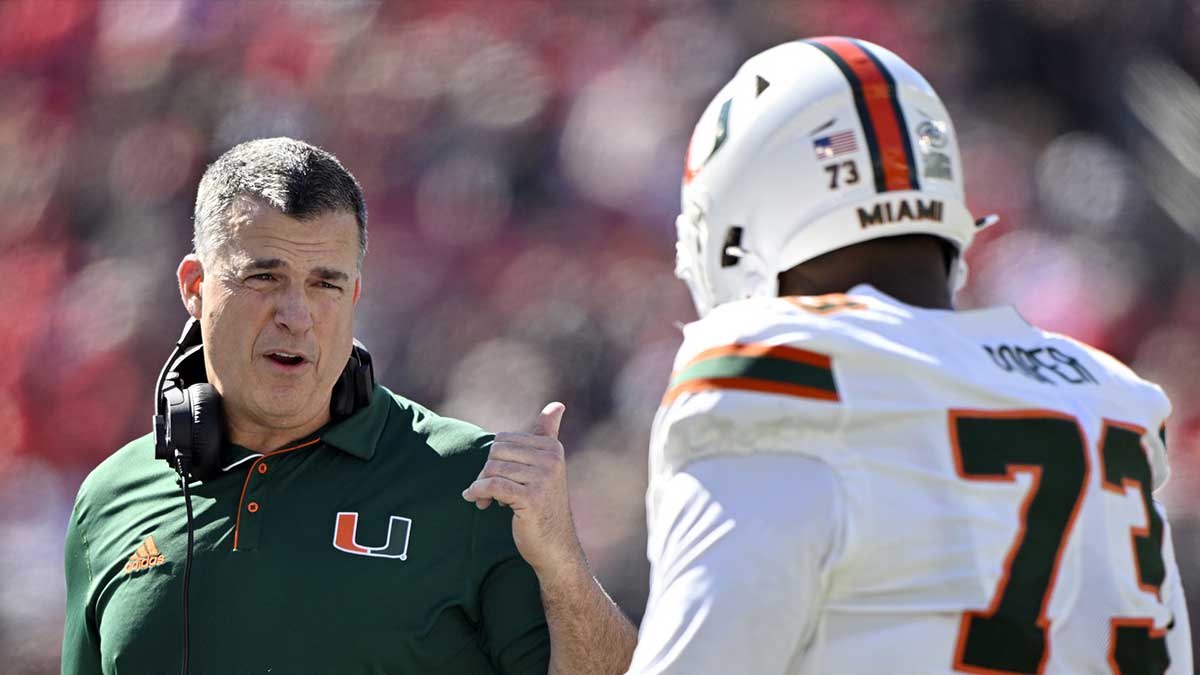 Oct 19, 2024; Louisville, Kentucky, USA; Miami Hurricanes head coach Mario Cristobal talks with offensive lineman Anez Cooper (73) during the first half against the Louisville Cardinals at L&N Federal Credit Union Stadium. Mandatory Credit: Jamie Rhodes-Imagn Images