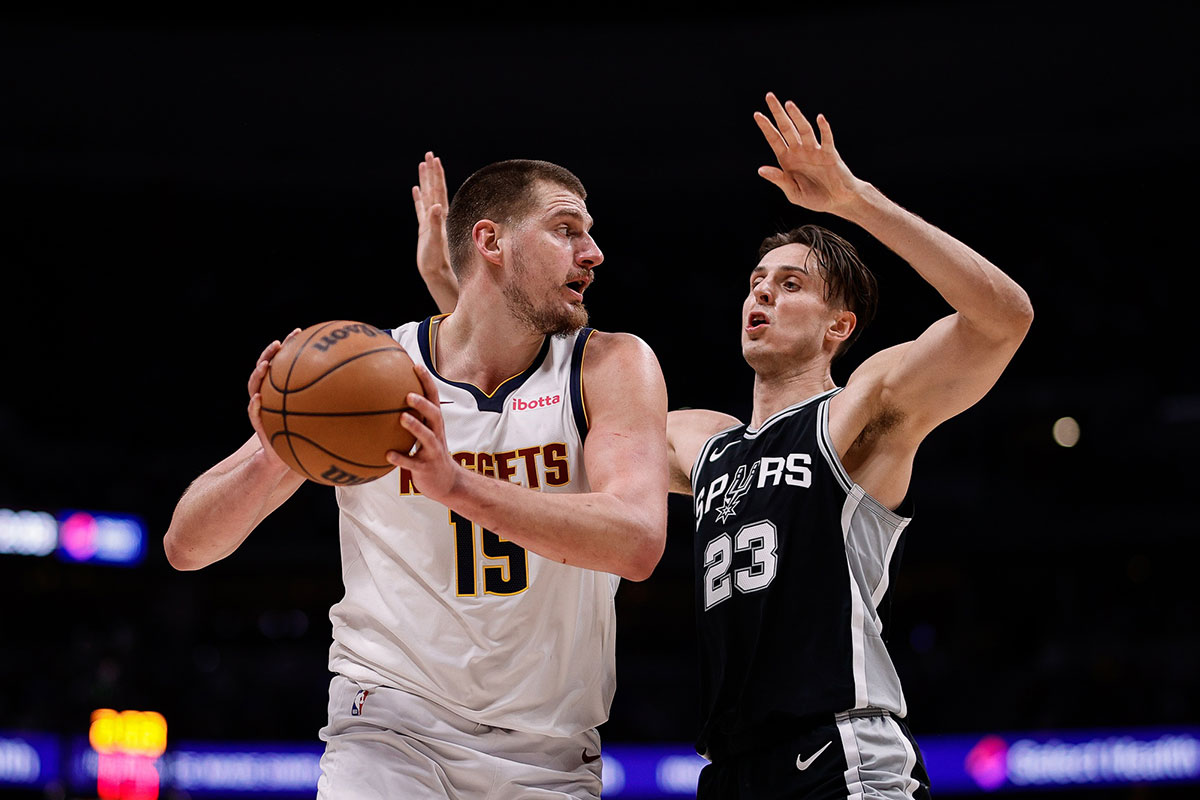 Denver Nuggets center Nikola Jokic (15) controls the ball as San Antonio Spurs forward Zach Collins (23) guards in the third quarter at Ball Arena.
