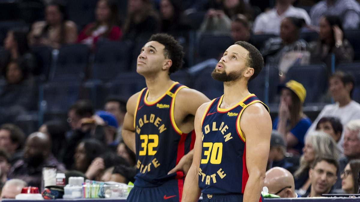 Golden State Warriors forward Trayce Jackson-Davis (32) and guard Stephen Curry (30) watch a reply during the fourth quarter against the Miami Heat at Chase Center.