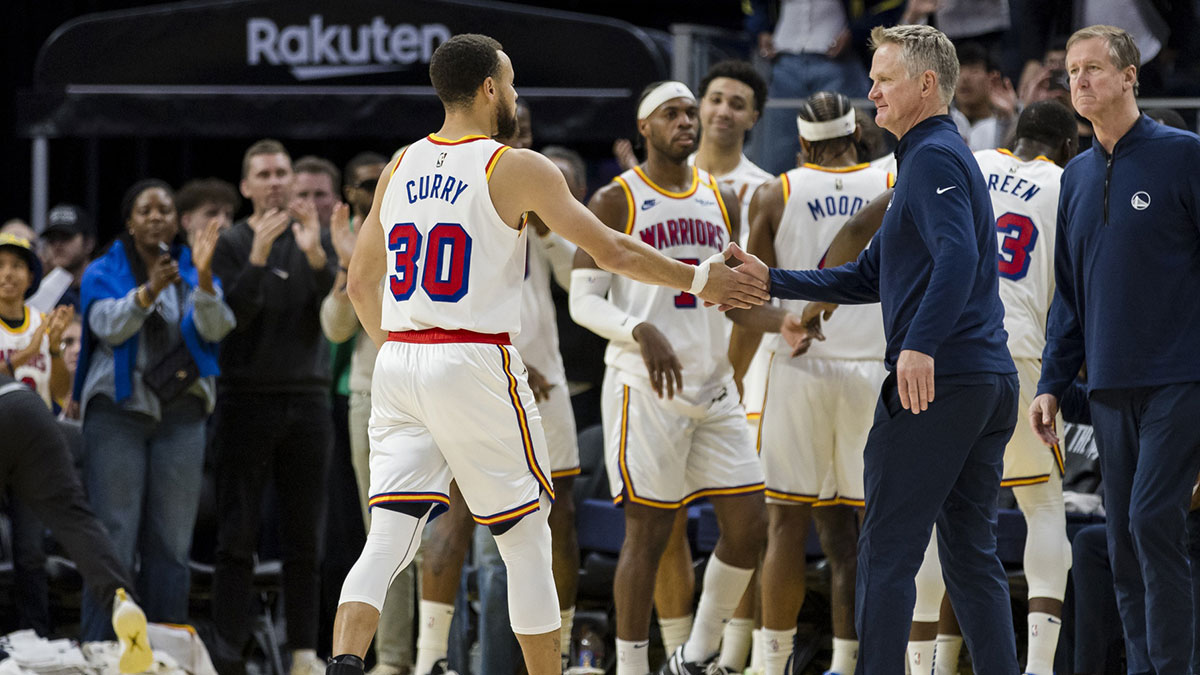 El base de los Golden State Warriors, Stephen Curry (30), es felicitado por el entrenador en jefe Steve Kerr cerca de la final del cuarto cuarto contra los Philadelphia 76ers en el Chase Center.