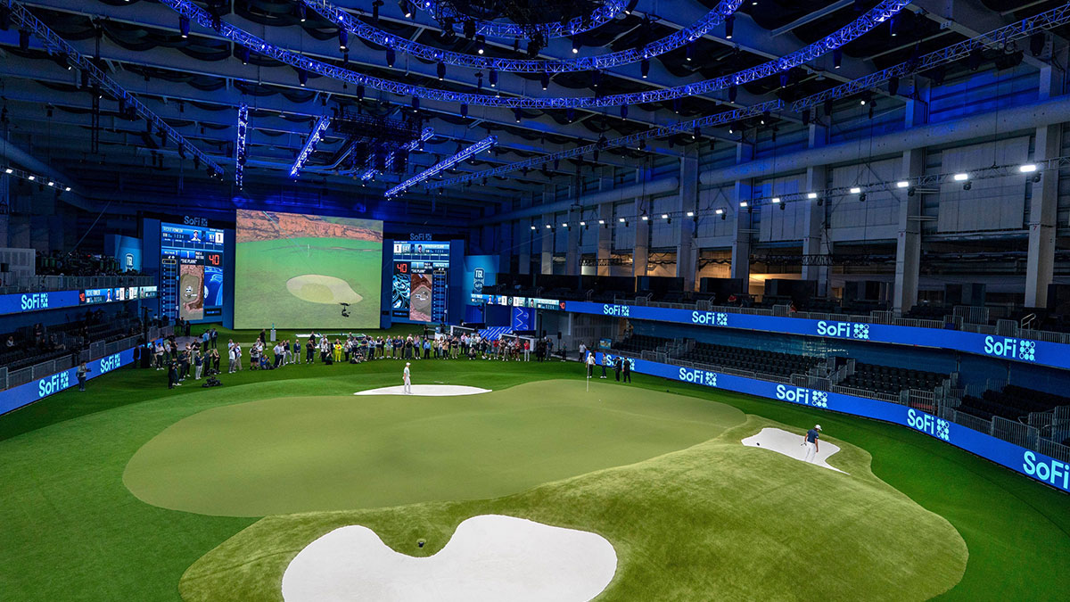 Golfers Wyndham Clark, center, and Rickie Fowler prepare to hit the ball out of the bunkers during media day at the SoFi Center, the home of TGL, the interactive golf league founded by Tiger Woods and Rory McIlroy