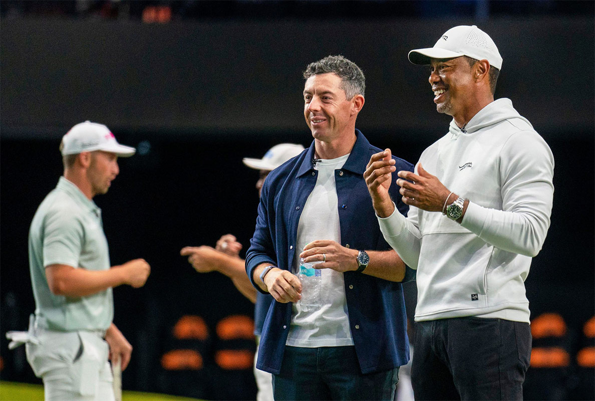Rory McIlroy and Tiger Woods watch golfers warm up for the inaugural match at SoFi Center, the home of TGL, the interactive golf league founded by Woods and McIlroy