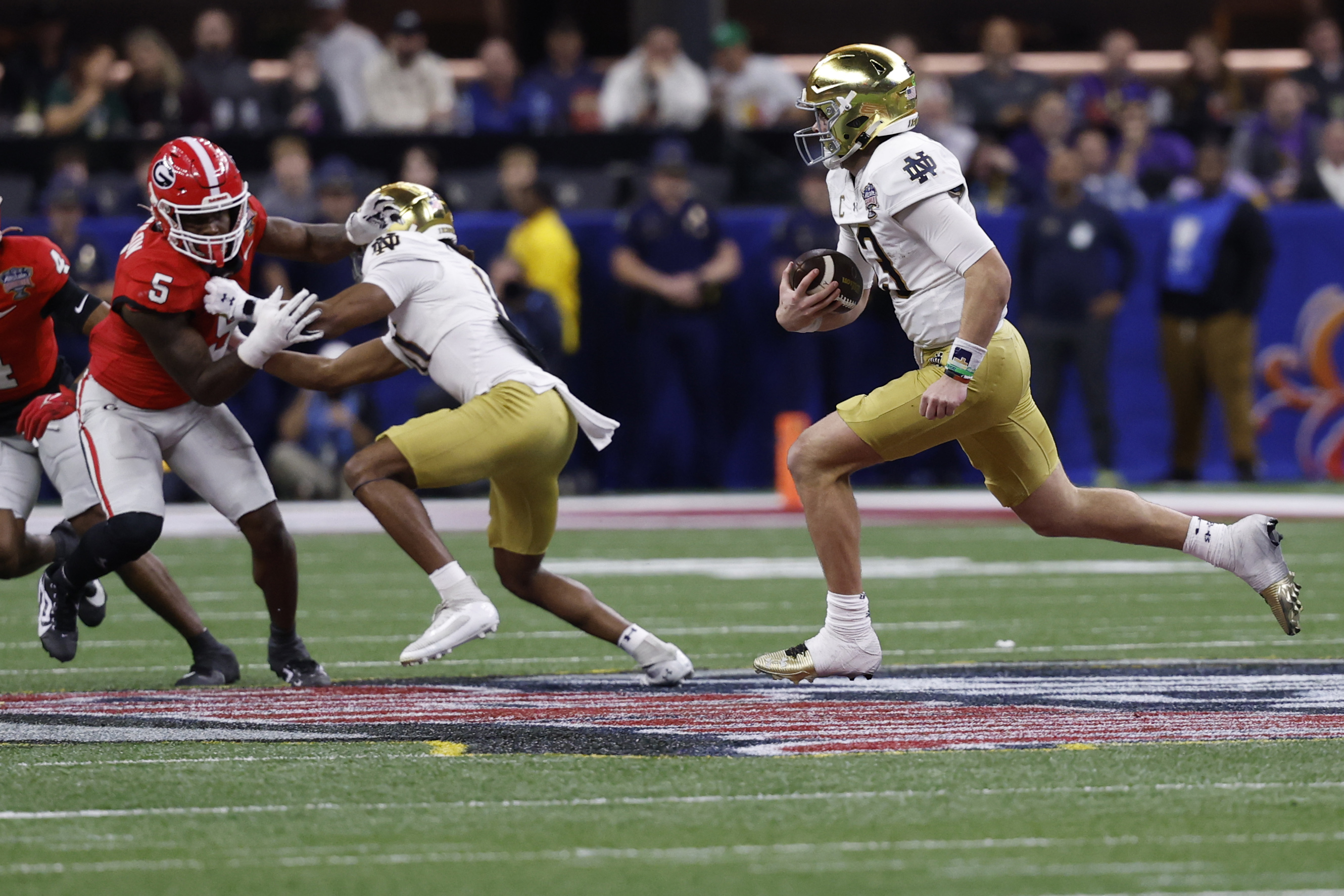 Notre Dame Fighting Irish quarterback Riley Leonard (13) runs with the ball as Georgia Bulldogs linebacker Raylen Wilson (5) chases during the third quarter at Caesars Superdome.