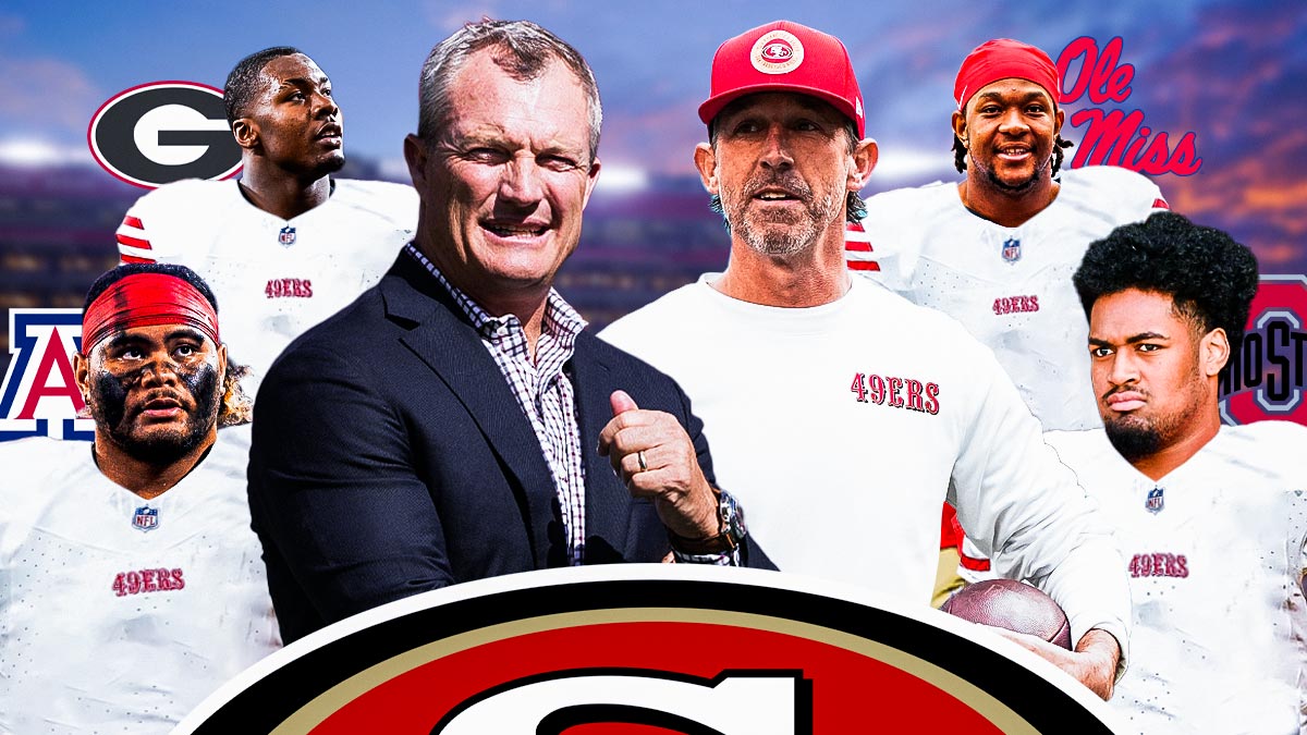 Kyle Shanahan and John Lynch standing next to Jonah Savaiinaea (in a Niners uniform with the Arizona Wildcats logo behind him), Josh Simmons (in a Niners uniform with the Ohio State logo behind him), Mykel Williams (in a Niners uniform with the Georgia logo in the background), and Jared Ivey (in a Niners uniform with the Ole Miss logo in the background).