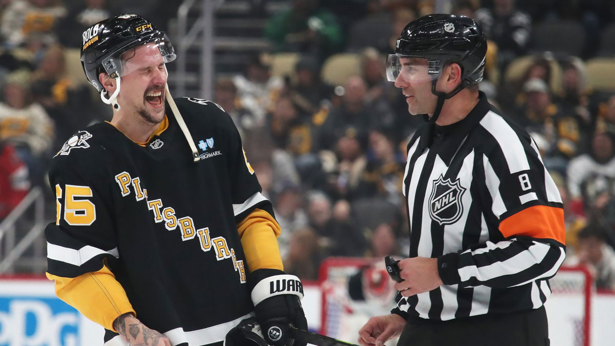 Pittsburgh Penguins defenseman Erik Karlsson (65) shares a laugh with referee Francois St. Laurent (8) in overtime against the New Jersey Devils at PPG Paints Arena. 