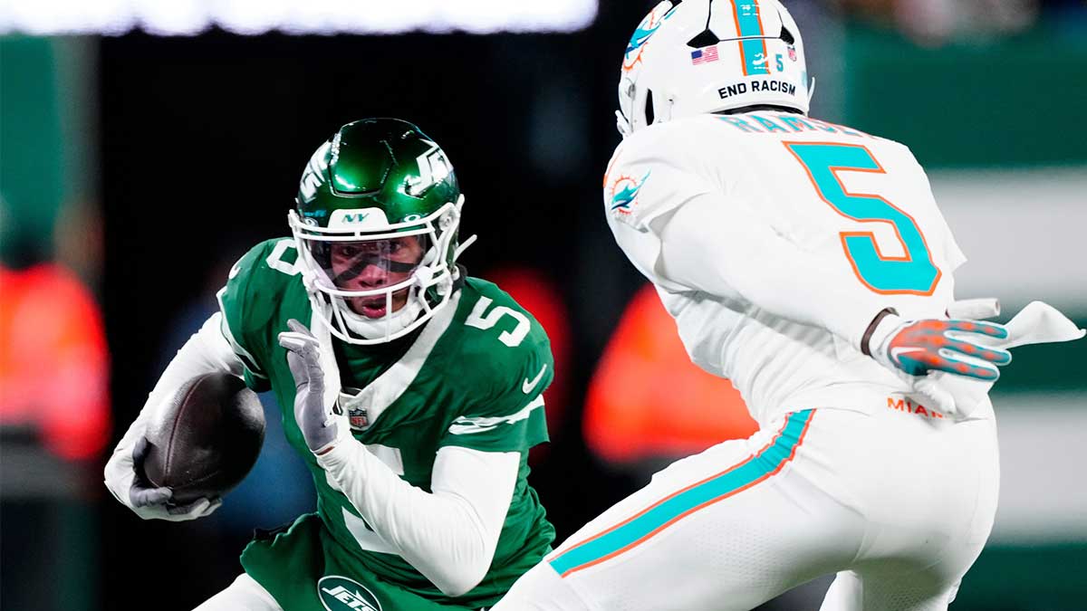 New York Jets wide receiver Garrett Wilson (5) runs with the ball as he tries to find a way past Miami Dolphins cornerback Jalen Ramsey (5), Sunday January 5, 2025, in East Rutherford.