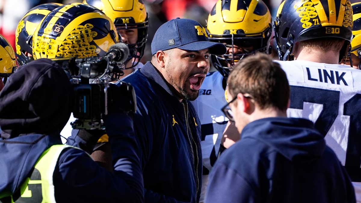 Michigan offensive line coach Grant Newsome talks to players in a huddle during warm up before the game between Ohio State and Michigan at Ohio Stadium