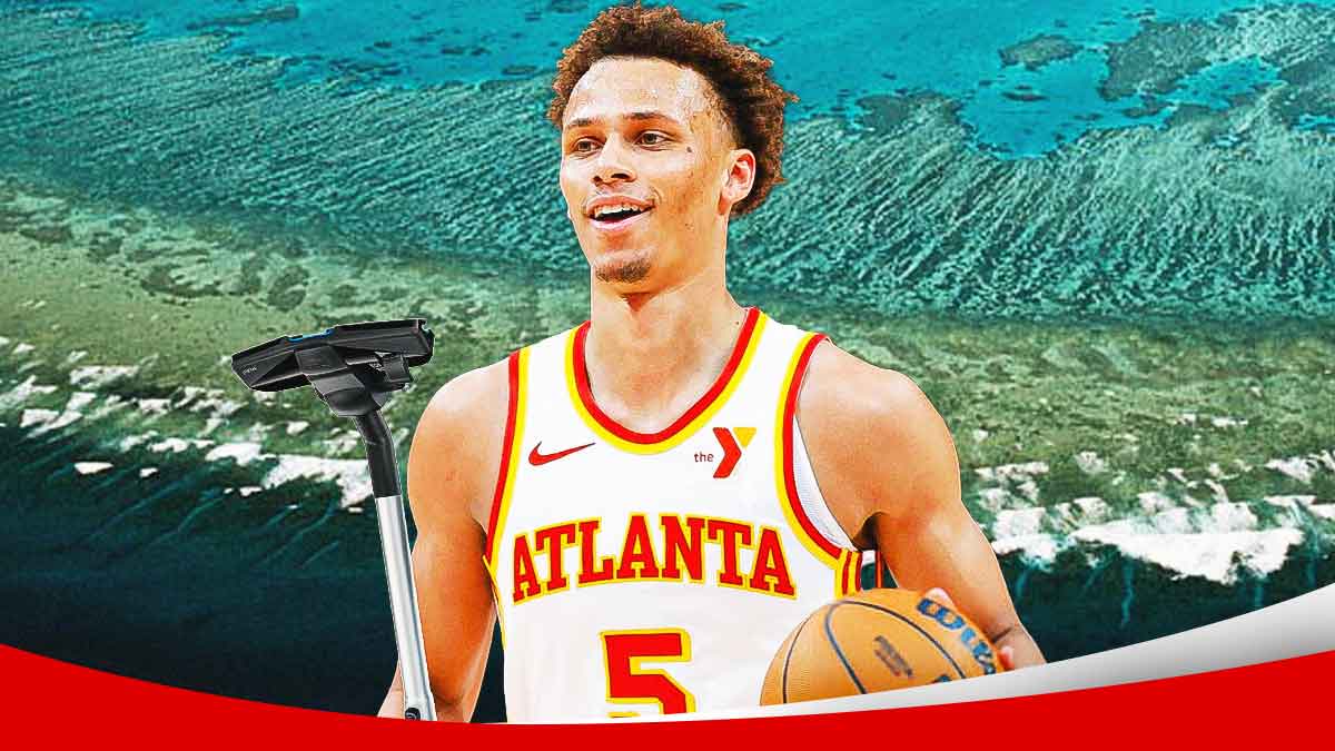 Hawks' Dyson Daniels smiling while holding a vacuum, with Great Barrier Reef in the background