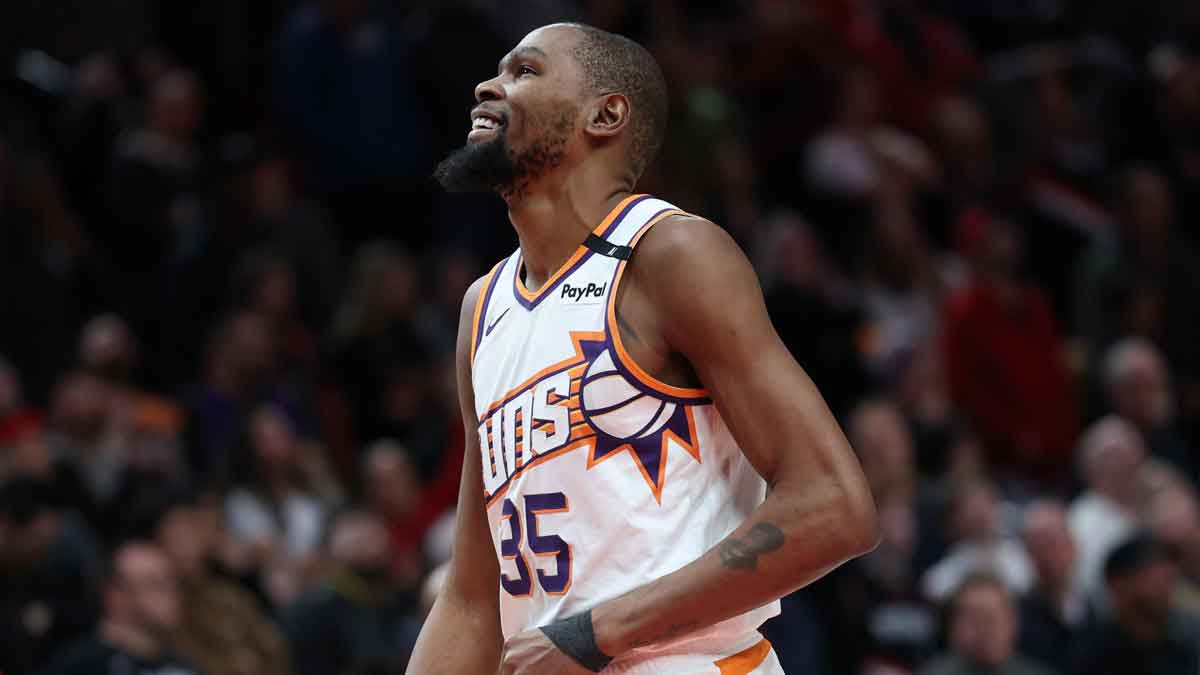 凤凰城的前锋凯文·杜兰特（Kevin Durant）（35岁）笑了，他看着他的队友太阳队的后卫德文·布克（Devin Booker）（1）在莫达中心的加时赛中被波特兰开拓者队的前锋迪尼·阿维加（Deni Avdija）犯规。