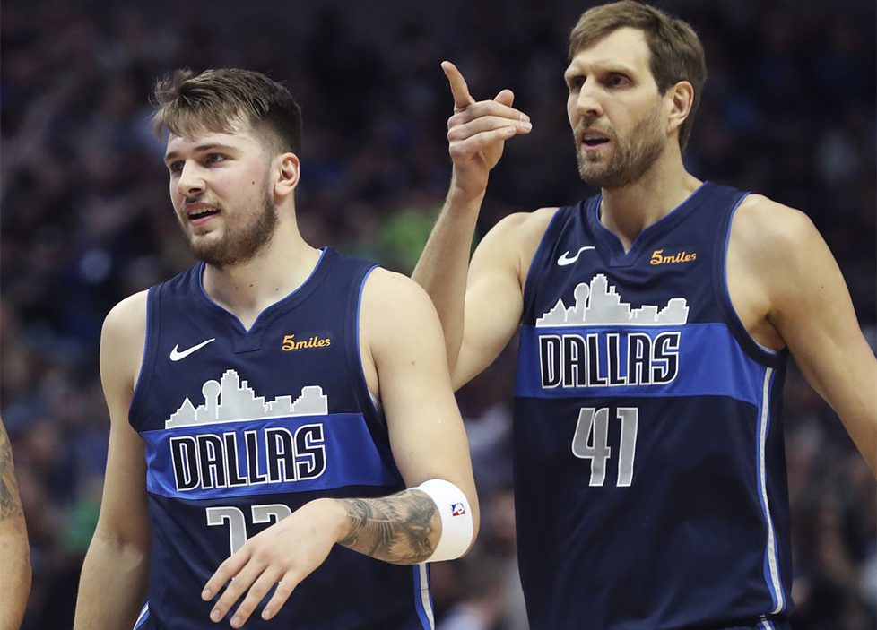 Luka Doncic and Dirk Nowitzki walk towards the bench