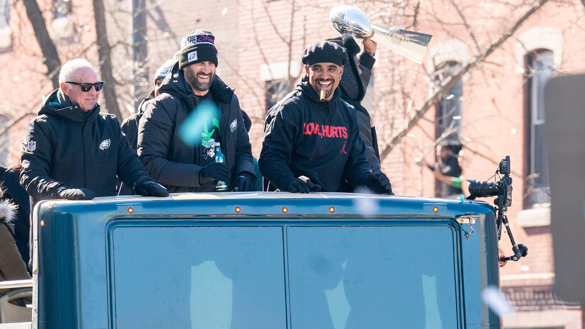 Philadelphia Eagles owner Jeffrey Lurie, left, joins head coach Nick Sirianni and quarterback Jalen Hurts atop one of the team buses during the Super Bowl 59 victory parade along S. Broad Street in Philadelphia
