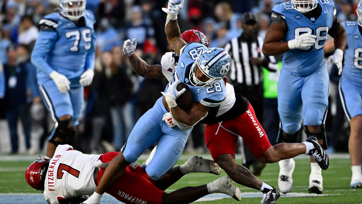 North Carolina Tar Heels running back Omarion Hampton (28) with the ball as North Carolina State Wolfpack safety Bishop Fitzgerald (7) and safety DK Kaufman (5) defend in the second quarter at Kenan Memorial Stadium.