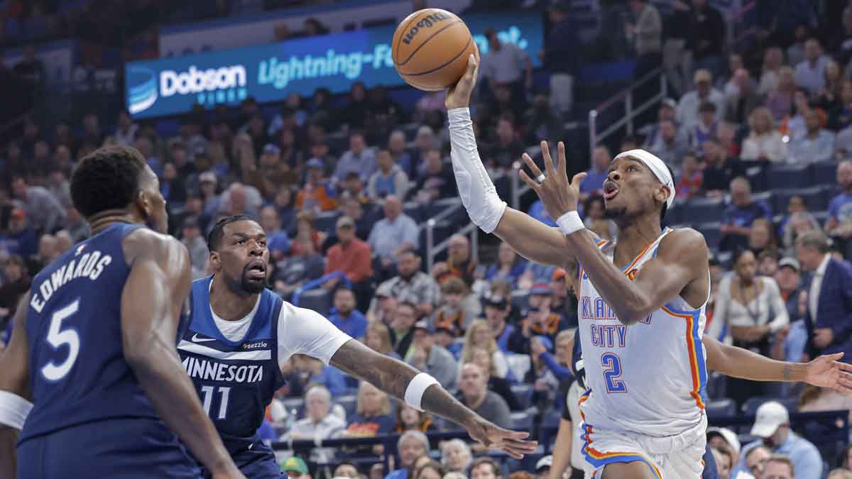 Oklahoma City Thunder guard Shai Gilgeous-Alexander (2) shoots as Minnesota Timberwolves center Naz Reid (11) and guard Anthony Edwards (5) defend during the first quarter at Paycom Center.