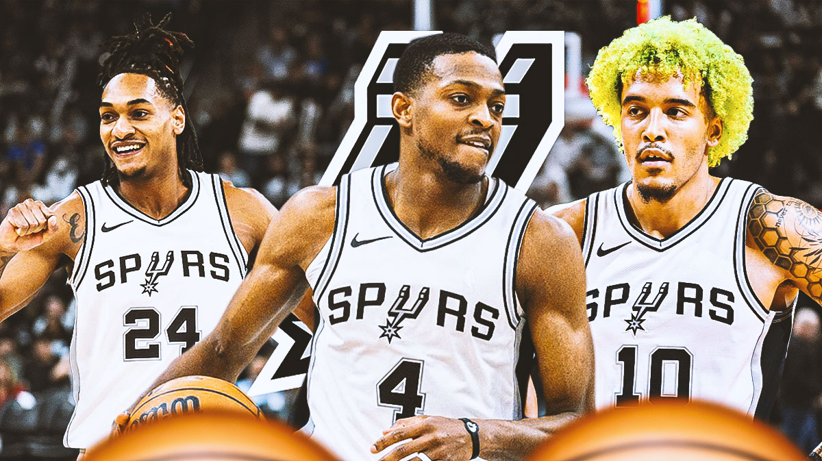 Spurs guard De'Aaron Fox next to Spurs forwards Devin Vassell and Jeremy Sochan with the Spurs logo in the background