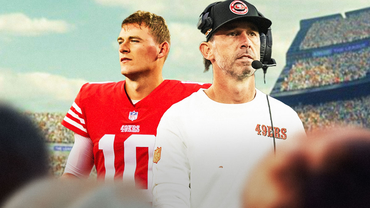 Kyle Shanahan next to Mac Jones wearing a 49ers uniform in front of the 49ers stadium.