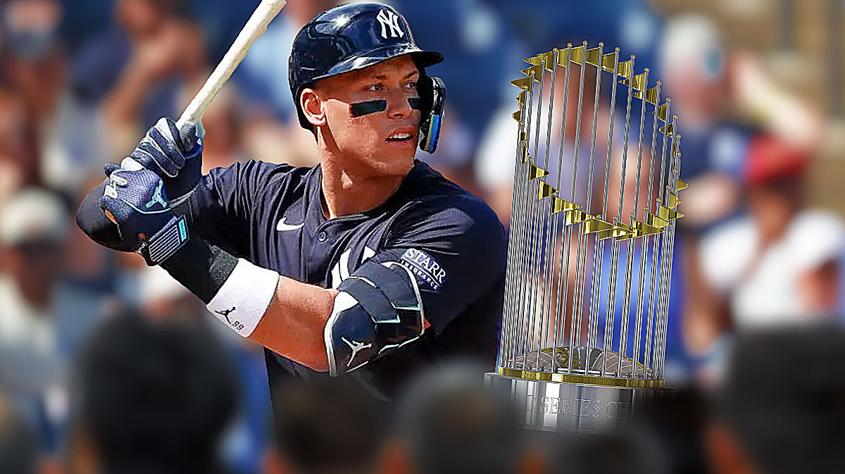 New York Yankees star Aaron Judge next to the World Series trophy in front of Yankee Stadium.