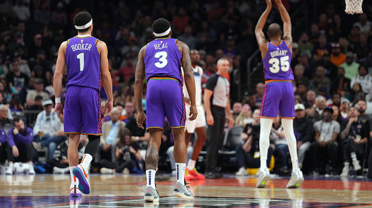 Phoenix Suns guard Devin Booker (1) and Phoenix Suns guard Bradley Beal (3) watch as Phoenix Suns forward Kevin Durant (35) shoots a free throw against the Minnesota Timberwolves during the first half at Footprint Center.