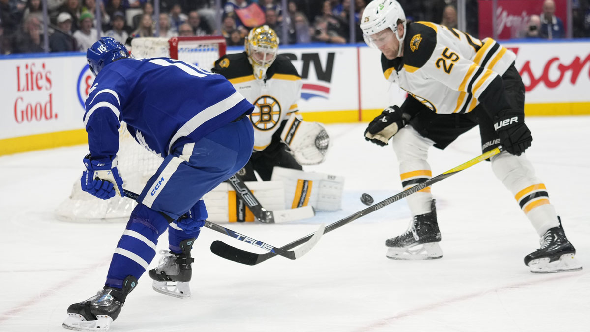 Toronto Maple Leafs forward Mitch Marner (16) shoots the puck from between his legs as Boston Bruins defenceman Brandon Carlo (25) and goaltender Jeremy Swayman (1) defends during the first period at Scotiabank Arena.