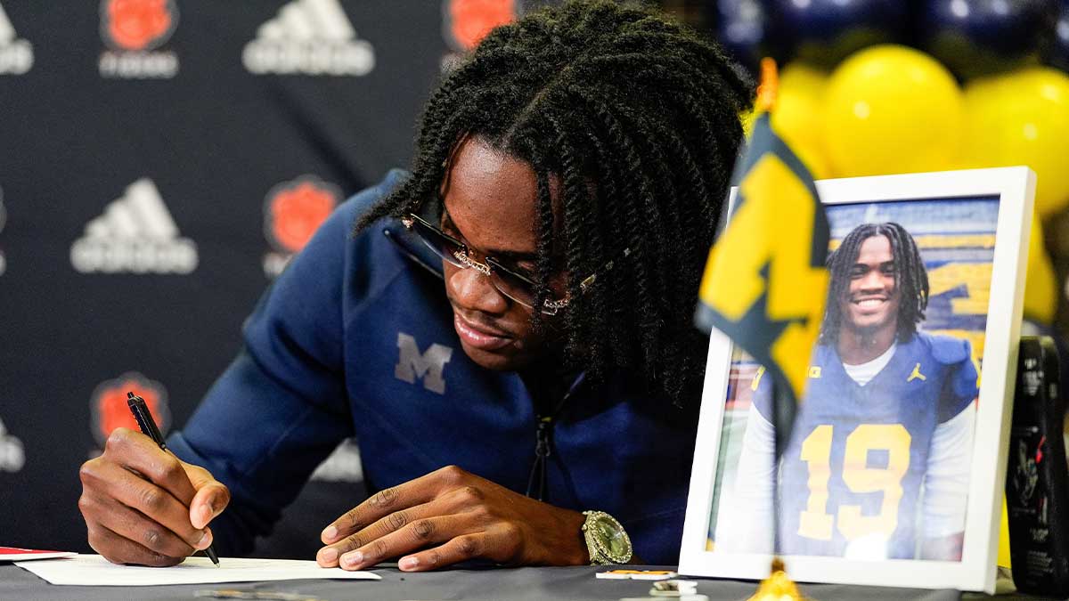 Michigan football signee Bryce Underwood poses for a photo as he signs for Michigan football on during national signing day at Belleville High School