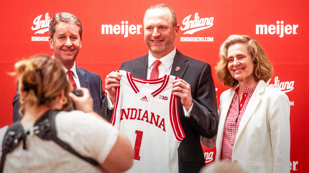 Indiana University Vice President and Director of Intercollegiate Athletics Scott Dolson, Indiana University men's basketball Head Coach Darian DeVries and Indiana University President Pamela Whitten pose with a jersey at the introductory press conference at Simon Skjodt Assembly Hall on Wednesday, March 19, 2025.