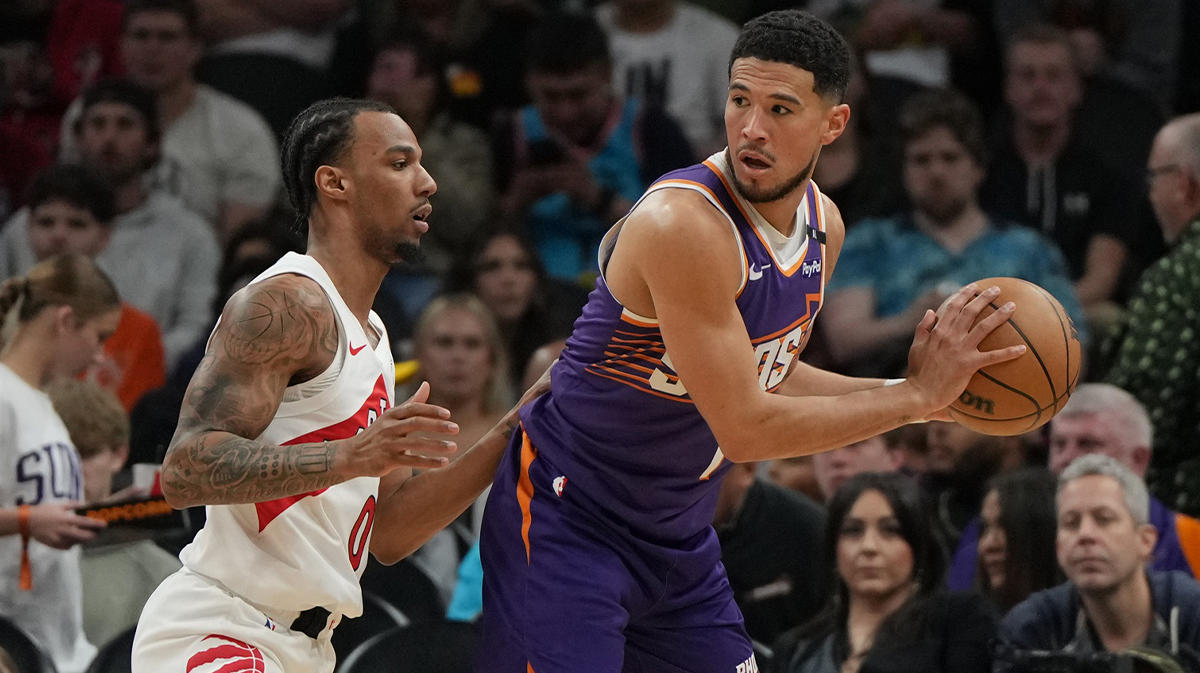 Phoenix Suns guard Devin Booker (1) shields the ball from Toronto Raptors guard A.J. Lawson (0) in the first half at Footprint Center.