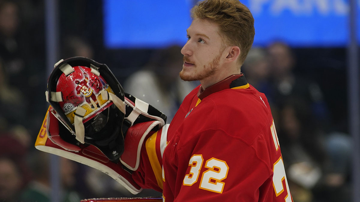 Calgary Flames goaltender Dustin Wolf (32) goes to put on his mask before a game against the Toronto Maple Leafs at Scotiabank Arena.