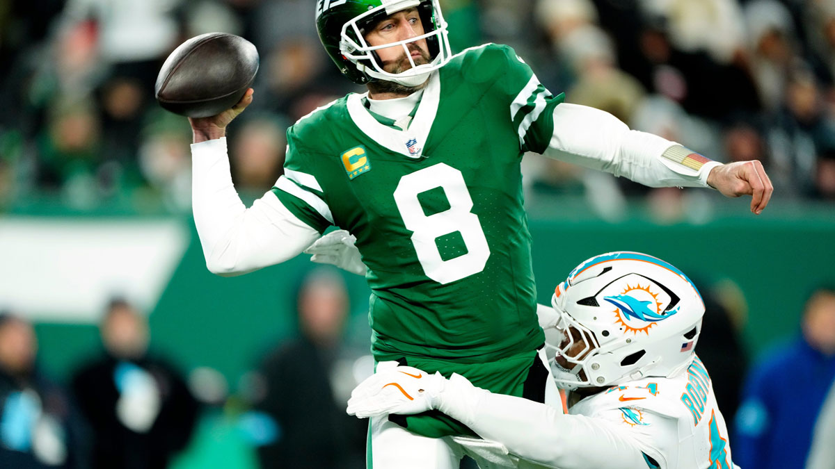 New York Jets quarterback Aaron Rodgers (8) throws a pass before Miami Dolphins linebacker Chop Robinson (44) could take him down, Sunday January 5, 2025, in East Rutherford.