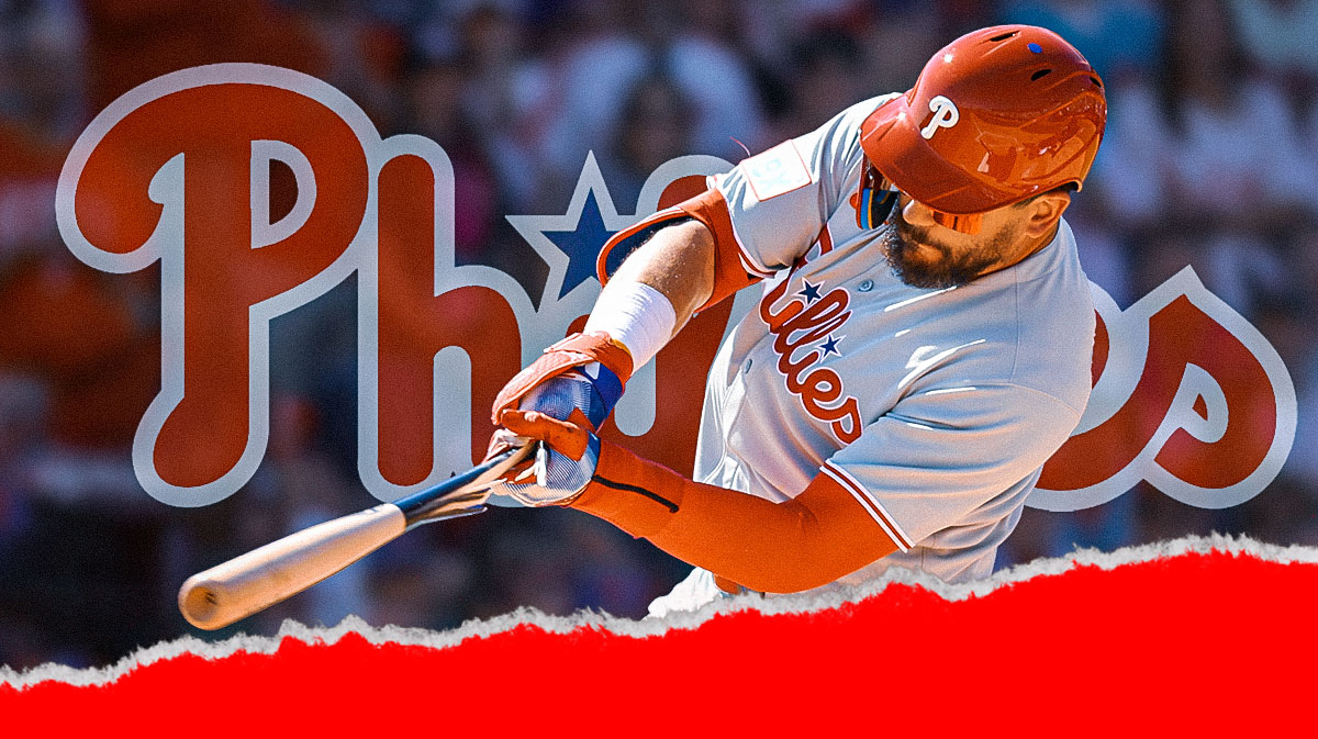 Kyle Schwarber in a Philadelphia Phillies uniform swinging a bat with Phillies logo behind him as Schwarber works on his swing for the phillies during spring training.