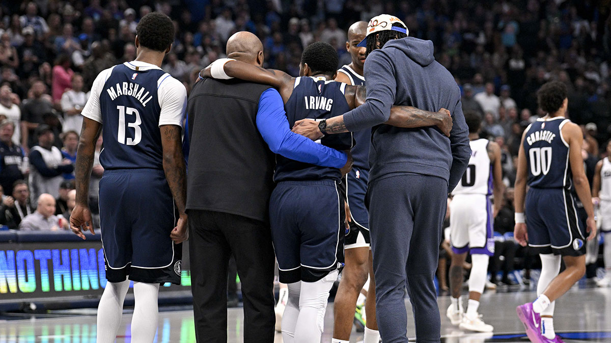 Dallas Mavericks guard Kyrie Irving (11) is helped off the court by forward Naji Marshall (13) and forward Anthony Davis (3) during the second quarter against the Sacramento Kings at the American Airlines Center.