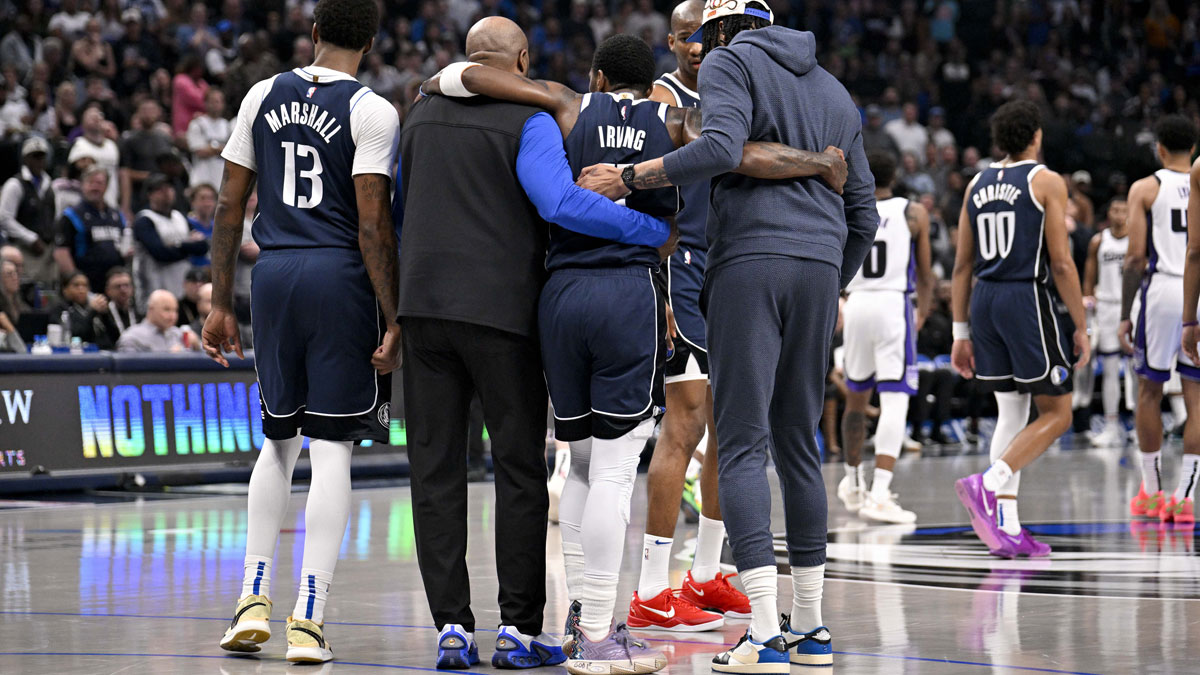 Dallas Mavericks guard Kyrie Irving (11) is helped off the court by forward Naji Marshall (13) and forward Anthony Davis (3) during the second quarter against the Sacramento Kings at the American Airlines Center.