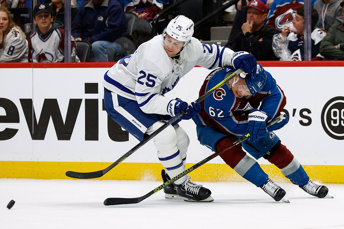 Toronto Maple Leafs defenseman Brandon Carlo (25) and Colorado Avalanche left wing Artturi Lehkonen (62) battle for the puck in the second period at Ball Arena.