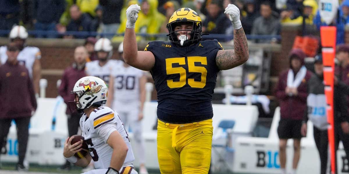 Michigan defensive lineman Mason Graham celebrates after sacking Minnesota quarterback Max Brosmer, in the background, during first-half action between Michigan and Minnesota