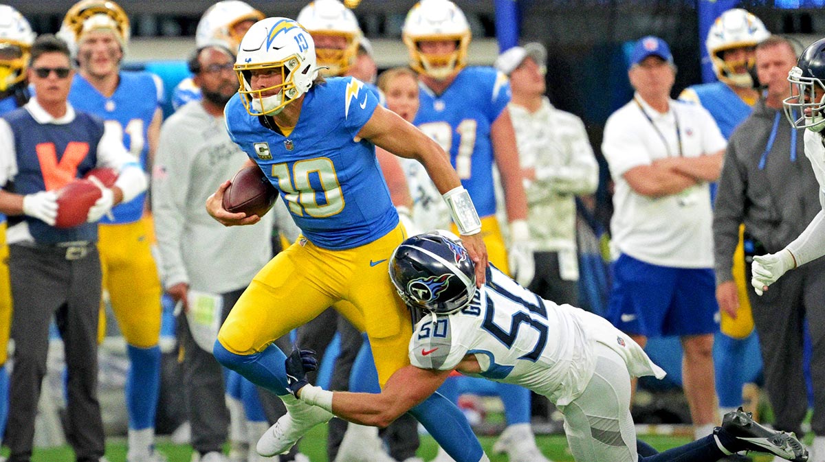 Los Angeles Chargers quarterback Justin Herbert (10) runs for a first down before he is stopped by Tennessee Titans linebacker Jack Gibbens (50) in the second half at SoFi Stadium.