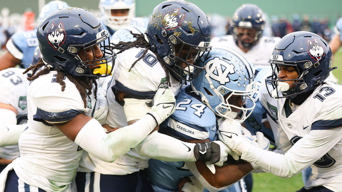 North Carolina's Darwin Barlow is tackled by, from left, UConn's Rante Jones, Jayden McDonald and Cam Chadwick during the third annual Wasabi Fenway Bowl at Fenway Park on Saturday, Dec. 28, 2024.