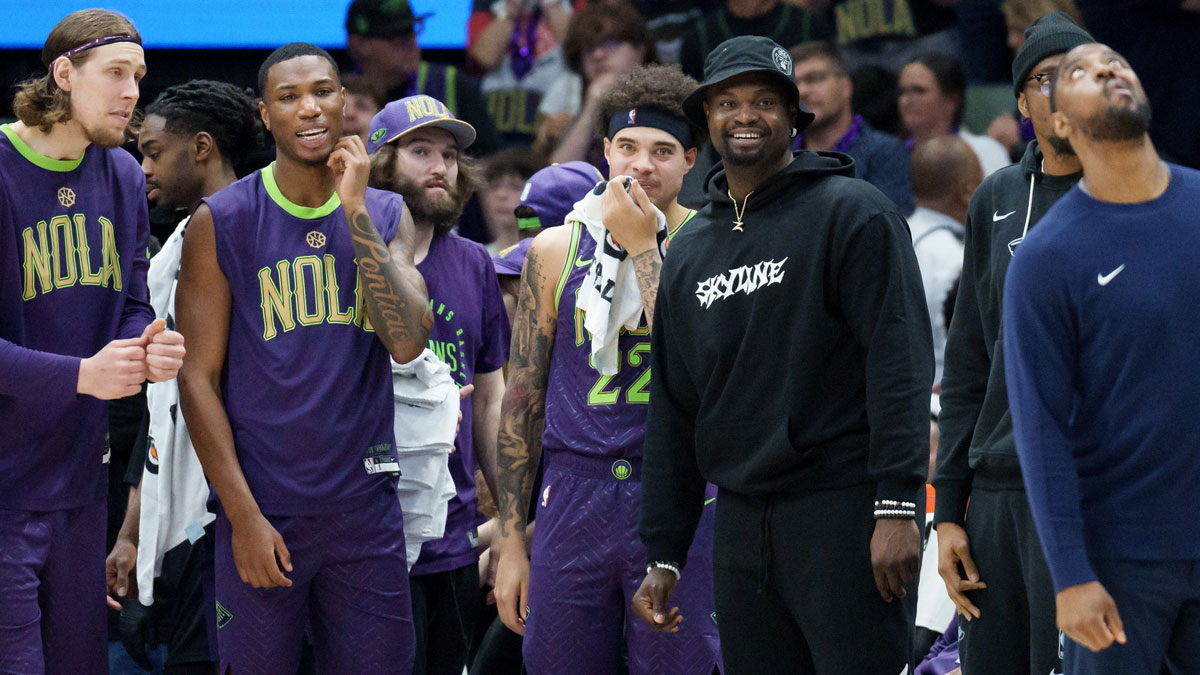 New Orleans Pelicans forward Zion Williamson, wearing street clothes and hat, smiles as his team gains a lead late during the fourth quarter against the Charlotte Hornets at Smoothie King Center.