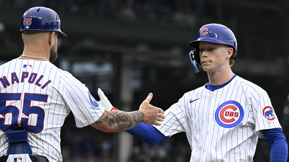 Chicago Cubs outfielder Pete Crow-Armstrong (right) shakes hands with first base coach Mike Napoli (55) after he hits an RBI single during the eighth inning against the Cincinnati Reds at Wrigley Field.