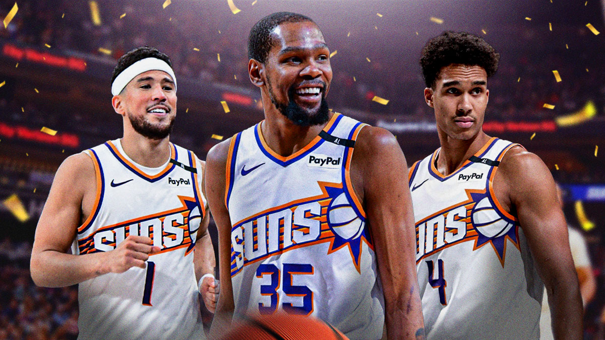 Suns stars Kevin Durant and Devin Booker smiling and laughing, with Oso Ighodaro also smiling around them. There is also confetti in the background, as well as the PHX Arena.