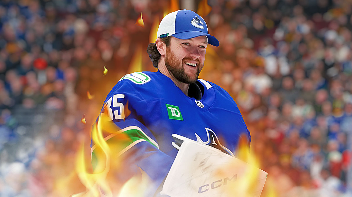 Thatcher Demko looking happy with fire around him, hockey rink in background