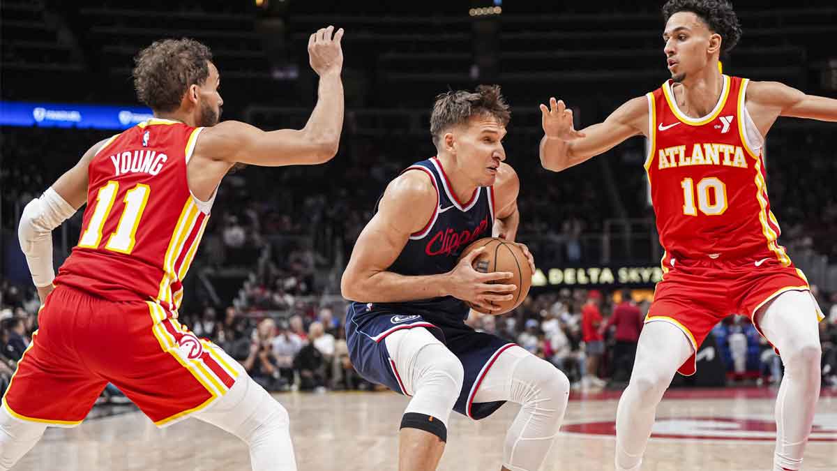 LA快船后卫Bogdan Bogdanovic（10）在下半场在州农场竞技场上处理亚特兰大老鹰队后卫Trae Young（11）和前锋Zaccharie Risacher（10）之间的球。 