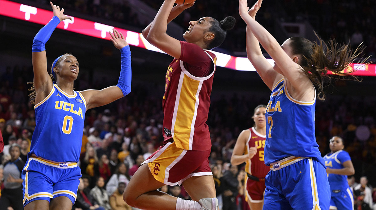 Feb 13, 2025; Los Angeles, California, USA; USC Trojans guard JuJu Watkins (12) drives to the basket between UCLA Bruins forward Janiah Barker (0) and guard Elina Aarnisalo (7) during the fourth quarter at Galen Center. Mandatory Credit: Robert Hanashiro-Imagn Images
