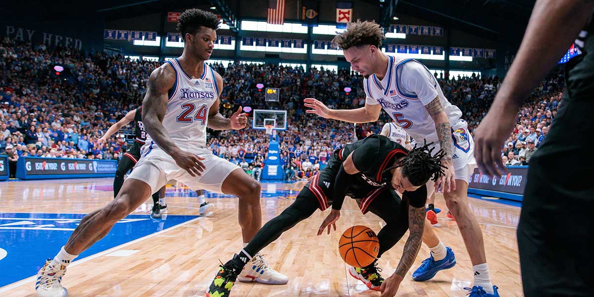 Texas Tech Red Raiders guard Elijah Hawkins (3) tries to keep control of the ball between Kansas Jayhawks guard Zeke Mayo (5) and forward KJ Adams Jr. (24) during the second half at Allen Fieldhouse.
