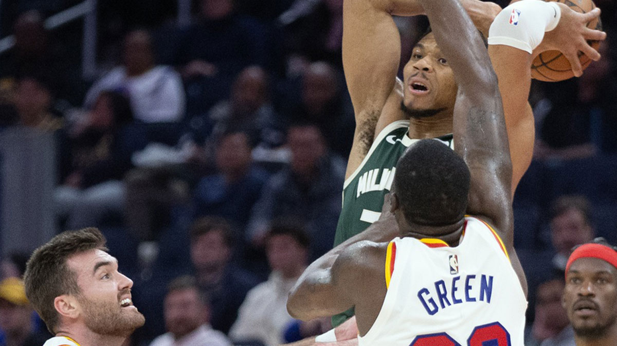 Milwaukee Bucks forward Giannis Antetokounmpo (34) leaves his feet to pass over Golden State Warriors defenders Pat Spencer (61) and Draymond Green (23) during the second quarter at Chase Center. 