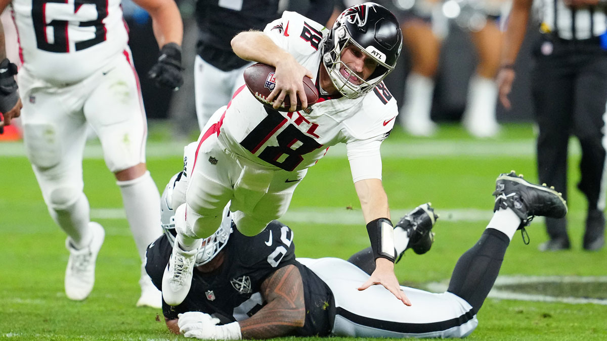 Atlanta Falcons quarterback Kirk Cousins (18) is tripped up by Las Vegas Raiders defensive tackle Jonah Laulu (96) during the second quarter at Allegiant Stadium.