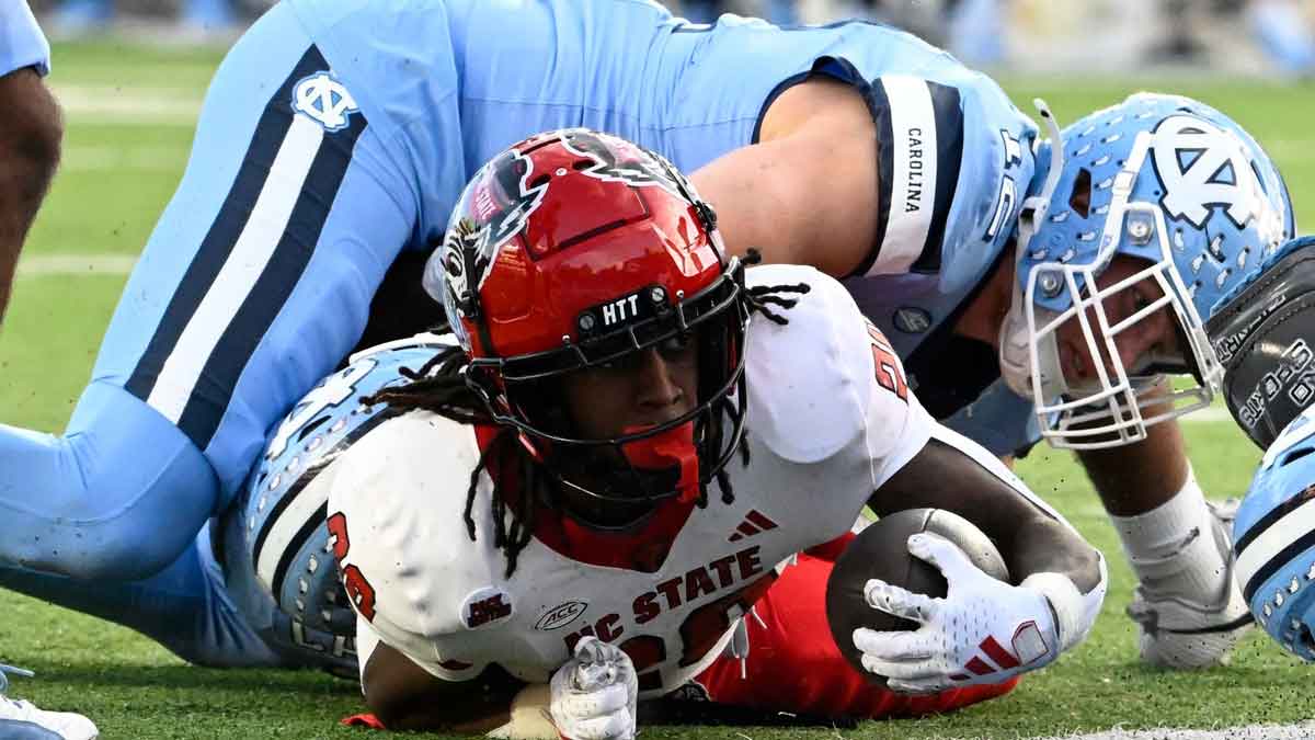 North Carolina State Wolfpack running back Hollywood Smothers (20) scores a touchdown as North Carolina Tar Heels defensive lineman Beau Atkinson (12) defends in the first quarter at Kenan Memorial Stadium. Mandatory Credit: Bob Donnan-Imagn Images