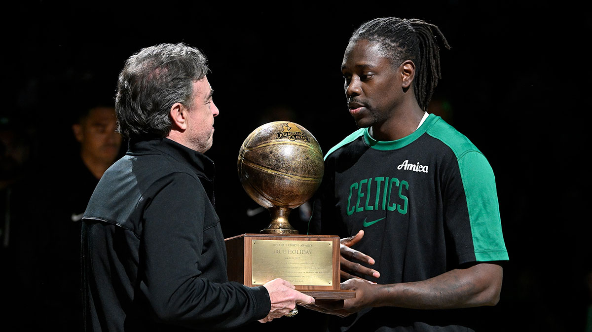 Celtics guard Jrue Holiday next to the Celtics logo