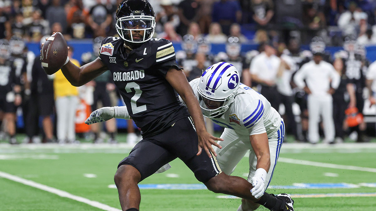 Colorado Buffaloes quarterback Shedeur Sanders (2) attempts to avoid a tackle by Brigham Young Cougars safety Raider Damuni (3) during the second quarter at Alamodome.